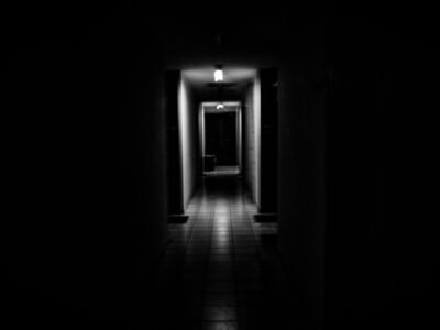 Corredor escuro com uma única luz acesa no fundo, sem que se veja o que há ali