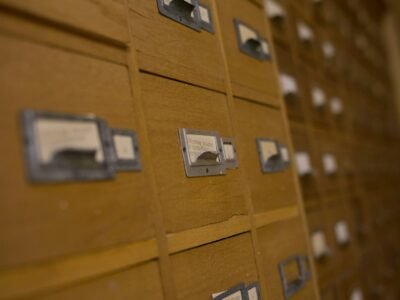 Parede de gavetas de madeira de um fichário de biblioteca, com etiquetas nas frentes