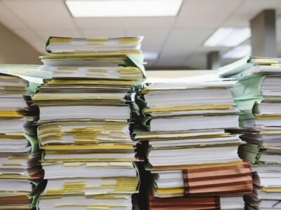 Pilhas altas de maços de papel com marcadores adesivos amarelos em uma sala de arquivo